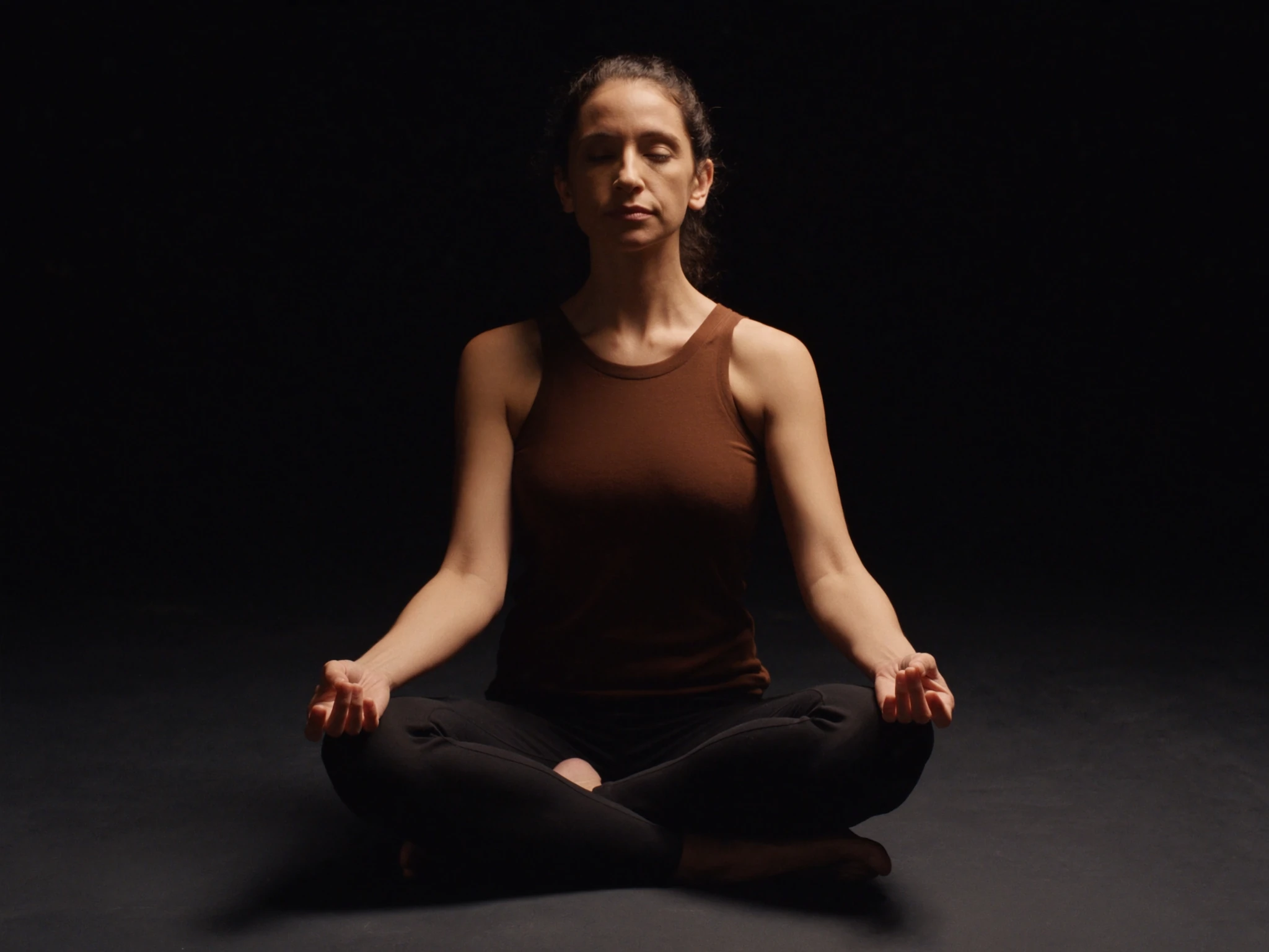 Persona meditando sentada junto a una ventana con luz tenue